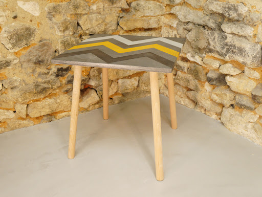 Table d'appoint en béton ciré de couleurs acier plume et moutarde avec motif aztèques et au pied style scandinave en bois