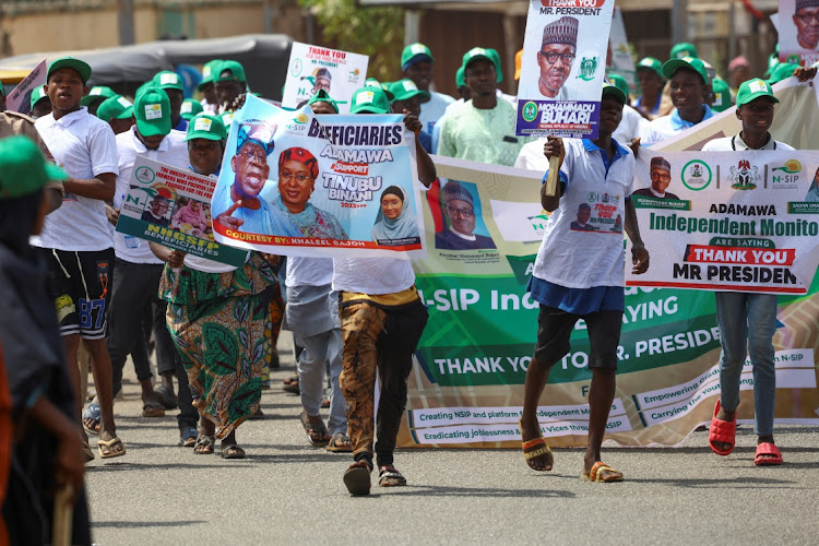 All Progressives Congress supporters hold posters and banners of Nigerian President Muhammadu Buhari and presidential candidate Bola Tinubu during a party campaign ahead of Nigeria's presidential elections in Yola, Nigeria, on February 22 2023.