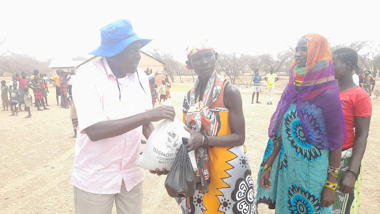 Retired Bishop Silas Yego of AIC distributes food items to hunger-stricken families at Kalemunyang in Loima subcounty.