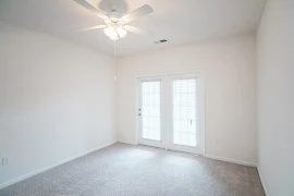 Bedroom features neutral carpet, light-colored walls, white ceiling fan, and patio door with blinds on far wall