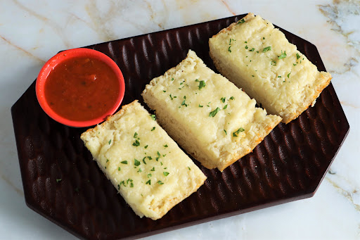 A platter of Cheesy Garlic Bread with marinara sauce.