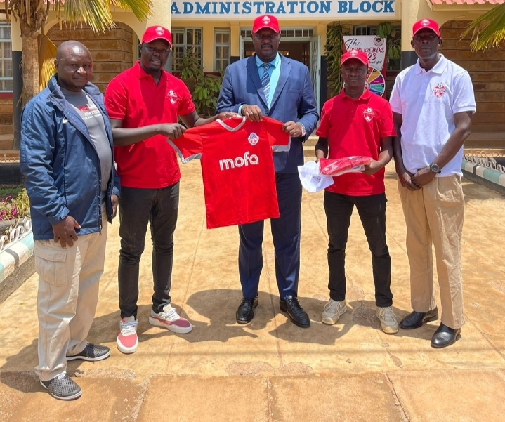 MOFA academy's Victor Olunga (second left) presents a jersey to Agoro Sare high school principal James Momanyi.