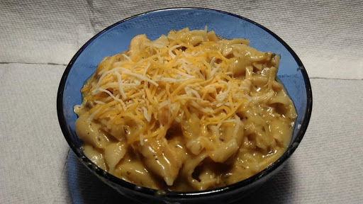 Cobalt blue bowl filled with cheesy chicken and seashell pasta.