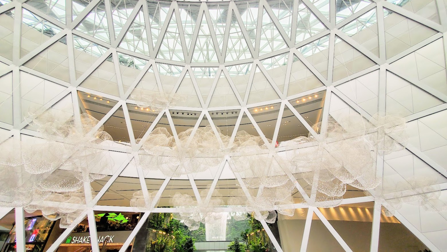 Visiting Changi Airport in Singapore: I really loved the view  of seeing the sparkle of the shimmering crystals in the sculpture Crystal Clouds while also seeing the flow of water from the Rain Vortex