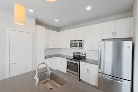 Fully equipped kitchen with white cabinets, stainless steel appliances, and a center island with pendant lighting