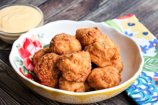 A bowl of Mashed Potato Bites with cheese sauce on the side.