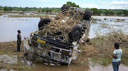 Locals look at a wreck washed away during tropical storm Ana on the flooded Shire river, an outlet of Lake Malawi at Thabwa village, in Chikwawa district, southern Malawi, on January 26 2022.