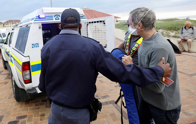 A police officer arrests a protester at the Muizenberg beach for contravening lockdown regulations.