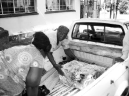 BEREAVED: Flora Manyike is helped by a relative to settle hergrandson's coffin in a bakkie at Tintswalo Hospital. 19/03/09. Pic. Riot Hlatshwayo. © Sowetan.