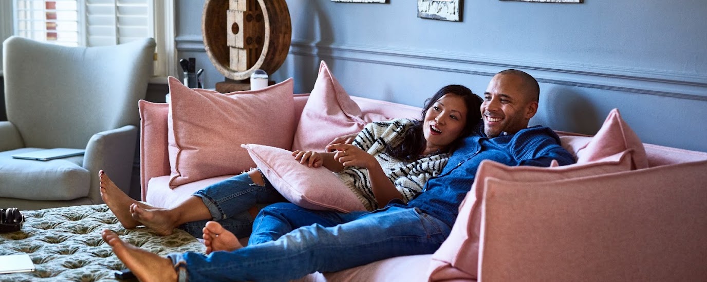 A couple sitting on the couch, streaming TV.