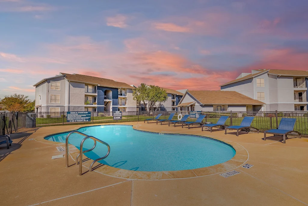 The Carmel Apartment's community pool with lounge chairs surrounding at dusk