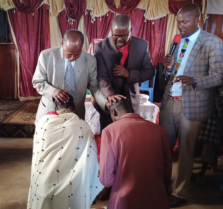 Bishop John Mpurkoi of Pentecostal Assemblies of God (PAG) Narok church (centre) with Rev Johnmark ole Keshe (left) pray for new pastor Sammy Yenko with his wife at Enengetia PAG church on Sunday, July 17