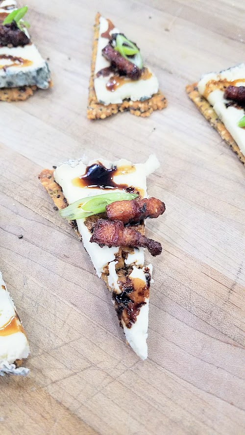 At the California Artisan Cheese Festival Best Bite Competition, Michele Wynne and Paige Icardi from Bi-Rite Market, San Francisco used Pluvius from Willapa Hills Cheese with a homemade super seed cracker, rind dust, ginger infused balsamic reduction, candied bacon, and scallions