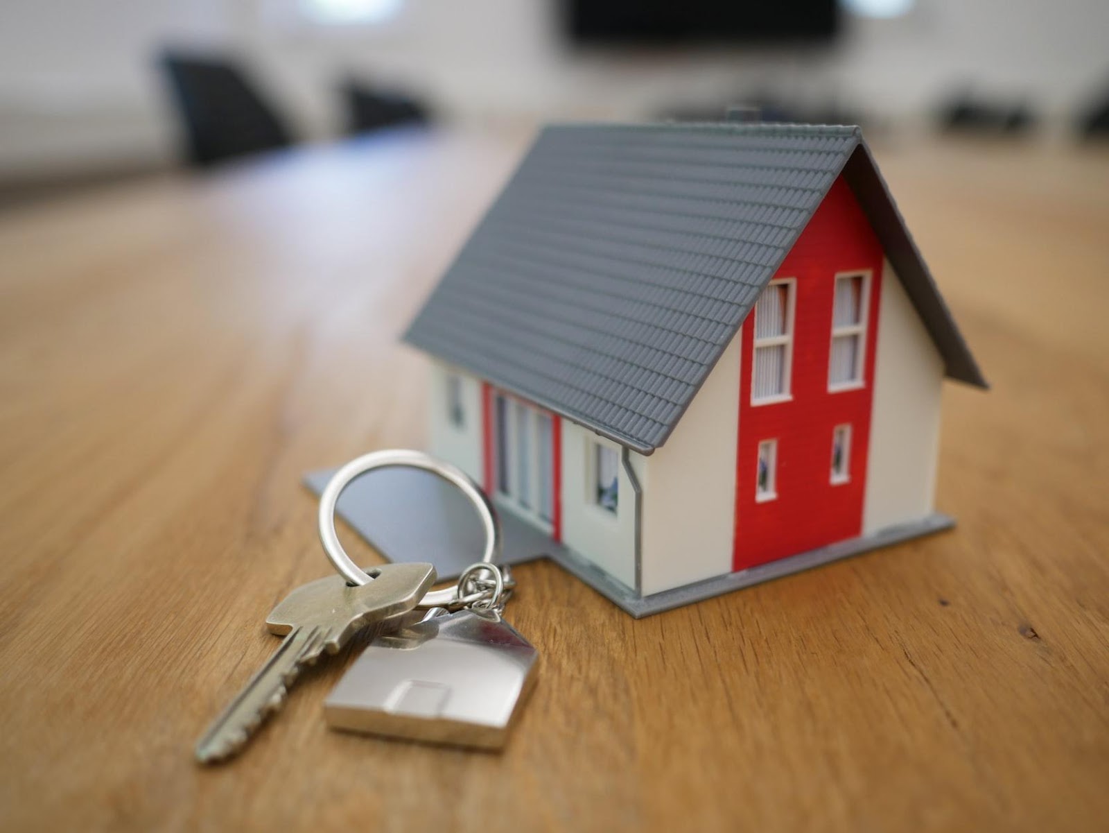 Miniature house and real key on a wooden surface 