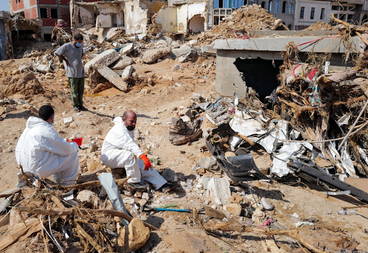 Libyans rescuers rest beside a damaged house in the aftermath of the floods in Derna, Libya, on September 16 2023.