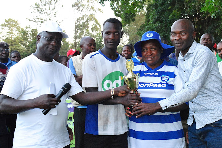 Isukha South MCA Charles Lwanga (L), Kakamega Woman Rep Elsie Muhanda (2nd R) and Emmanuel Makokha, the youth advisor to Kakamega governor, present a trophy to the Sambakhalu FC captain over the weekend