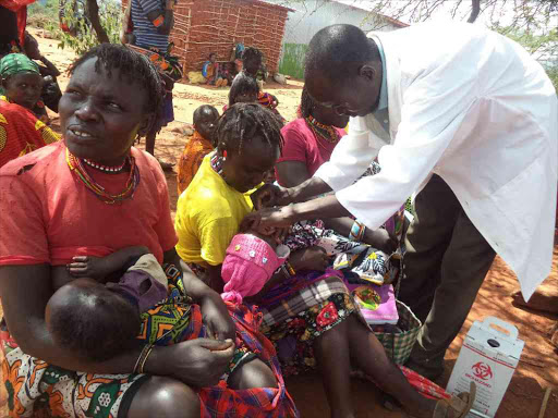 A health officer attends to children brought by their mothers to an open-air mobile clinic organised by World Vision International in Nachururu village, Tiaty subcounty, Baringo, in July last year. The subcounty is hard hit by famine /JOSEPH KANGOGO