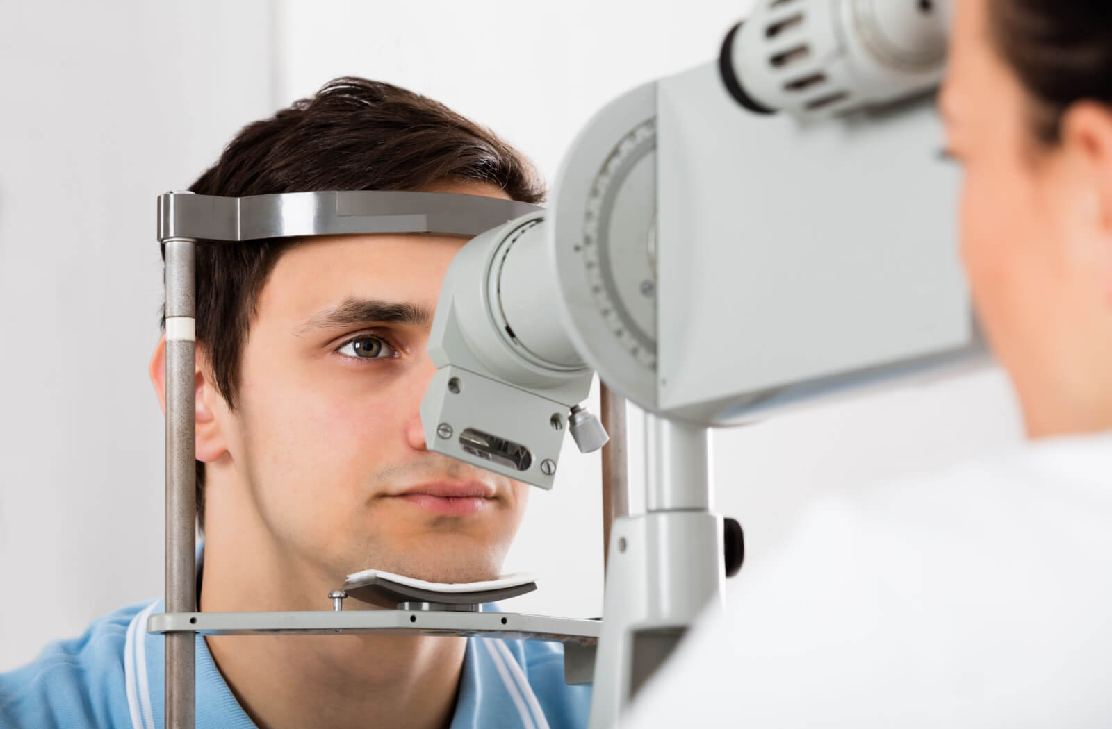 A man sitting in an ophthalmologist's office looking into a machine that tests his vision.