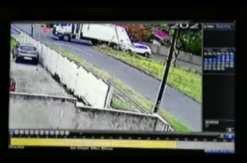 A refuse truck rollling backwards and bumping into a car behind it.