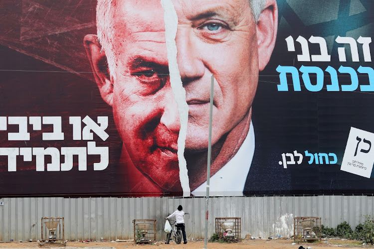 A boy looks up at a poster of former Israel defence minister Benny Gantz and Prime Minister Benjamin Netanyahu, left, in Bnei Brak, Israel, March 22, 2021. Picture: AMMAR AWAD/REUTERS