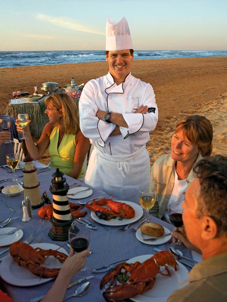 A chef  and guests at a lobster dinner on the beach on Prince Edward Island, Canada. 