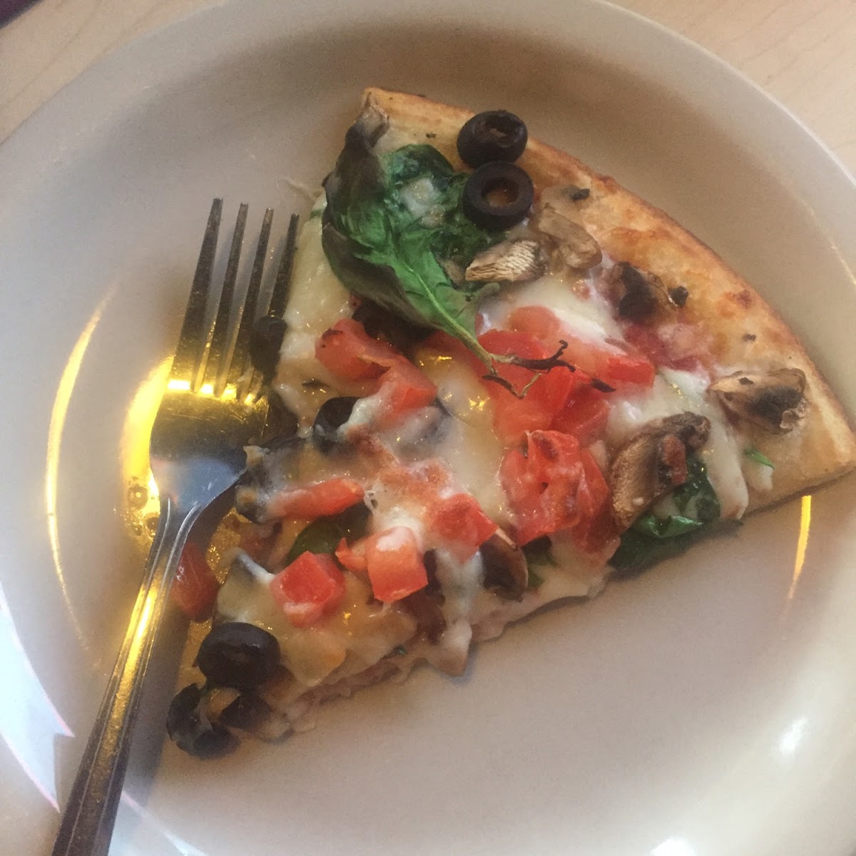 Gf pizza with tomato, spinach, mushrooms and olives.