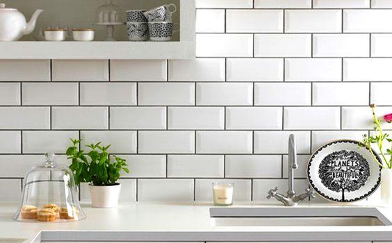 Pia de cozinha com bancada branca, parede da pia com azulejo subway tiles branco e nichos com objetos de cozinha