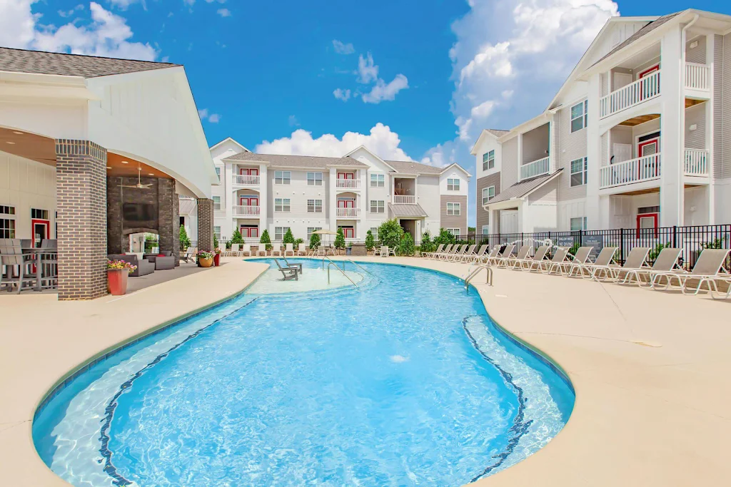 Community pool with clubhouse, lounge chairs, and apartment buildings in the background