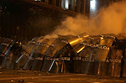 Police officers take cover with their shields during a clash with demonstrators during a protest against the decision of Congress to remove former president Martin Vizcarra, in Lima, Peru, on November 14 2020. 