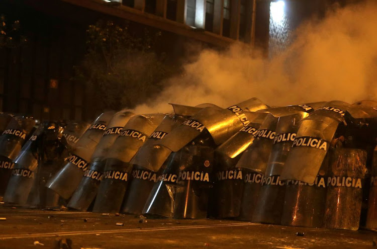 Police officers take cover with their shields during a clash with demonstrators during a protest against the decision of Congress to remove former president Martin Vizcarra, in Lima, Peru, on November 14 2020.