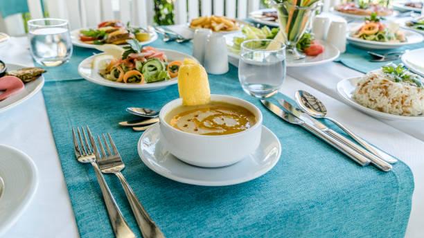 Traditional Turkish lentil soup for lunch A lunch setting with lentil soup in focus and a variety of traditional Turkish dishes on the background  Lemon Cayenne Pepper Water stock pictures, royalty-free photos & images