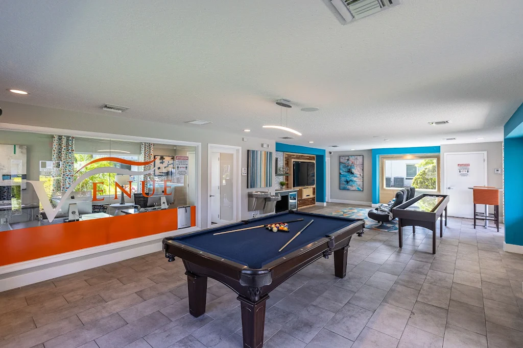 Clubhouse resident lounge with billiards table, shuffleboard, seating area and large TV