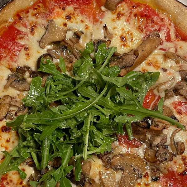 Neapolitan style pizza with tomato sauce, a roasted mushroom blend, truffle oil, mozzarella, arugula, and parmesan.

Can be made with plant-based cheese.