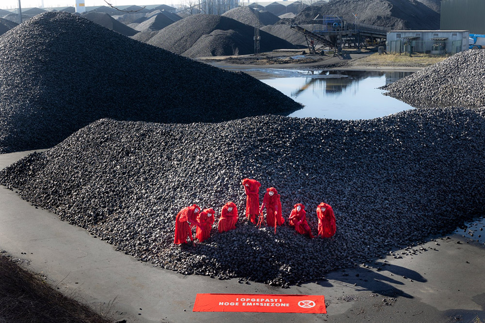 Red rebels line up across a vast pile of coal, one of many on the horizon.