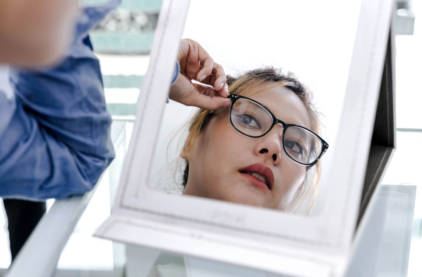 A girl in the mirror is fitting her new eyeglasses after her comprehensive eye exam.