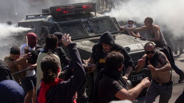 Demonstrators clash with a riot police vehicle in Santiago