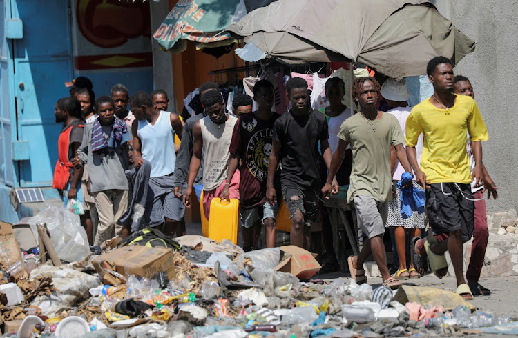 People wait to collect water in containers along a street after Haiti's Prime Minister Ariel Henry pledged to step down following months of escalating gang violence, in Port-au-Prince, Haiti March 12, 2024.