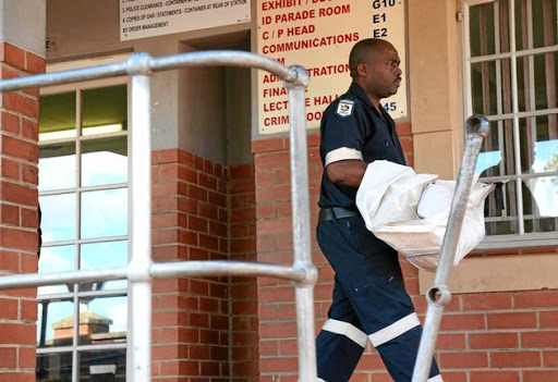 A mortuary attendant carries the body of two-year-old Jayden Khoza who died during protests in the Foreman Road informal settlement