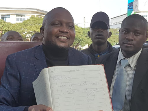 Moses Kuria with a visitors book earlier signed by President Uhuru Kenyatta during one of his stops in Kisumu on Saturday, July 21, 2018. /MAURICE ALAL