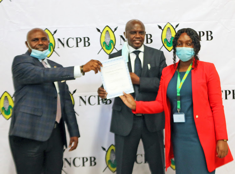 NCPB MD Joseph Kimote and Sorela Ltd MD Peter Mutuku present a certificate to NCPB quality officer Esther Lumumba when five aflatoxin labs were opened on Friday, December 11.