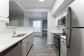 Kitchen with white upper & grey lower cabinets, stainless steel appliances, white quartz countertops, wood floors into dining