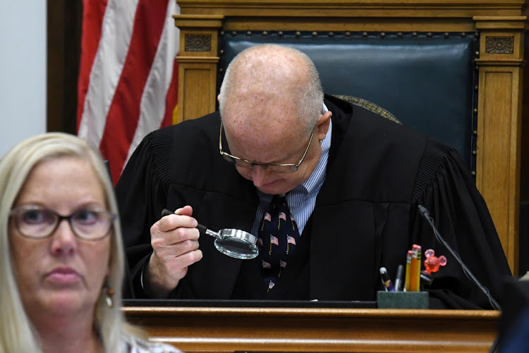 Judge Bruce E. Schroeder uses a magnifying glass to examine photographic enlargements during a dispute over the reliability of enlarged digital images during the Kyle Rittenhouse trial at the Kenosha County Courthouse in Kenosha, Wisconsin, US November 11, 2021.