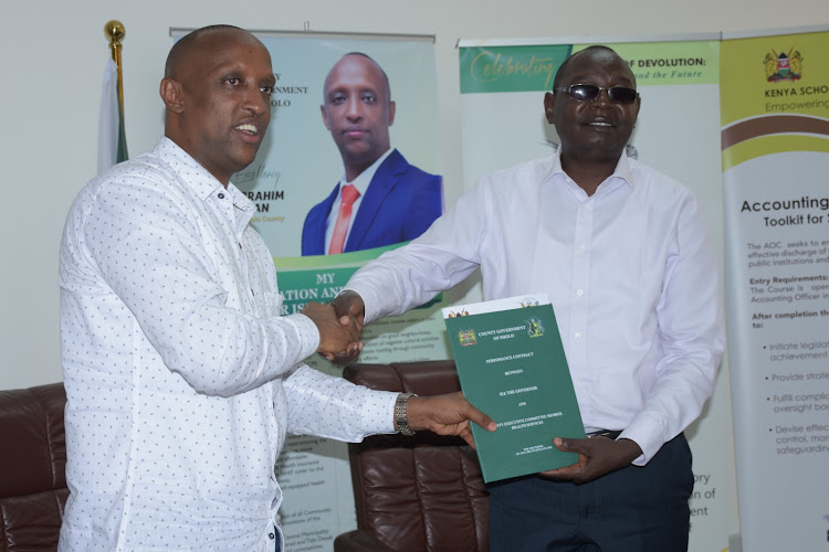 Isiolo Governor Abdi Hassan Guyo hands over a signed performance contract to his deputy, James Lowasa in Mombasa on September 21, 2023