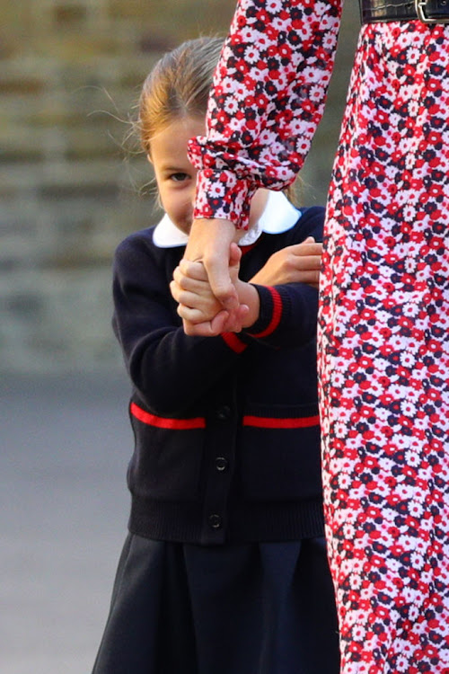 Princess Charlotte peeks out from behind her mother's dress at the photographers awaiting her arrival at her primary school.