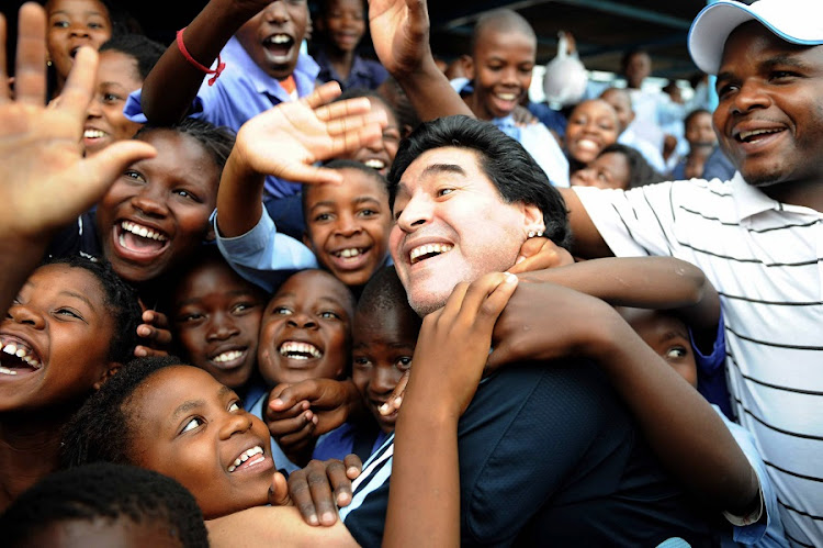 In this handout photo provided by 2010 Fifa World Cup Organising Committee South Africa, Argentina's head coach Diego Maradona is greeted by schoolchildren during his visit to Kgotlelelang School at Winterveldt, around 40km north west of Pretoria, South Africa on on January 19, 2010.