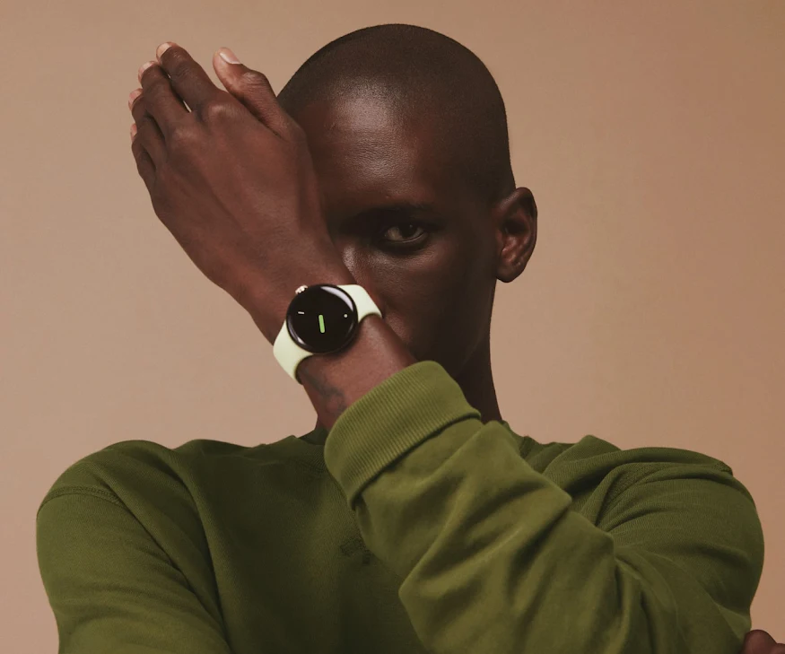 A person stylishly holds up their arm showing the Google Pixel Watch in front of their face