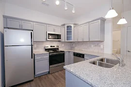 Kitchen with gray cabinets, marble-inspired countertops, tile backsplash, and stainless steel appliances