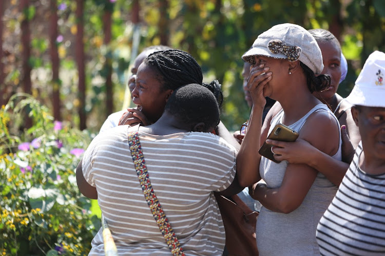 Distraught family members and residents react as a forensic pathology team removes the body of a six-year-old in White City, Soweto. Two children, aged five and six, were found mutilated this week after going missing.