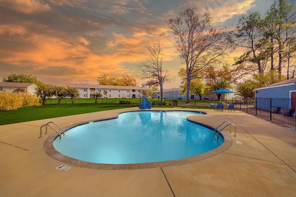 Cedar Run's swimming pool at dusk with a sundeck featuring picnic table, umbrella, and chairs