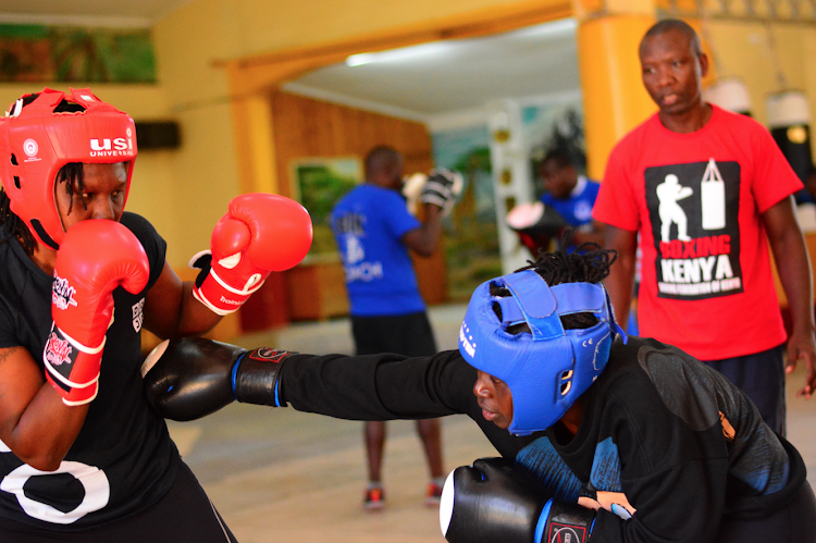 Elizabeth Andiego tries to evade a punch from Elizabeth Akinyi as coach David Munuhe looks on during a training session at Nanyuki social hall.